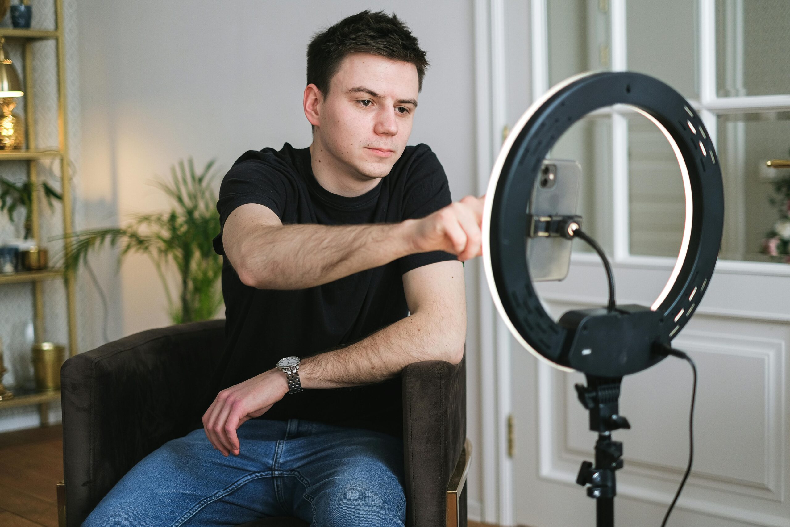 A man setting up a ring light while preparing to vlog indoors. Ideal for tech and lifestyle themes.